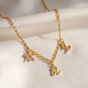 Primer plano de collar bañado en oro con dijes del zodiaco de circonita brillante.