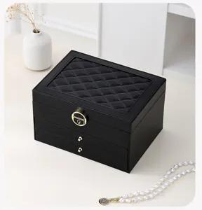 Close-up detail of the luxury black leather jewelry storage box with quilted top lid and gold lock.
