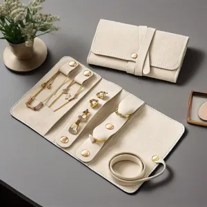 Portable beige velvet travel jewelry roll organizer for rings, necklaces, and earrings.