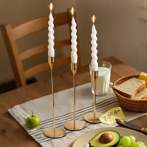 Nordic gold metal candle holders with twisted white candles for romantic dining table decor.