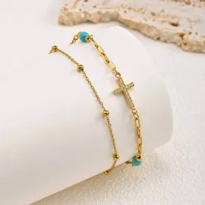 Gold double layer anklet detail with sparkling zirconia cross and turquoise beads.