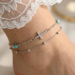 Close-up detail of a double layer silver anklet featuring a sparkling zirconia cross.