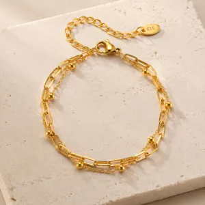 Bracelet doré double couche avec de petites perles et chaînes géométriques détail bijou.