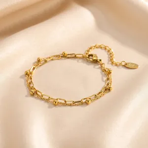 Bracelet doré double couche avec perles et chaîne fine et élégante avec pendentif.