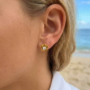 Close-up detail of 18k gold plated flower stud earrings with sparkling cubic zirconia on ear.