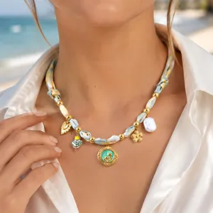 Gros plan détaillé du superbe collier foulard en tissu avec perles dorées et pendentifs.