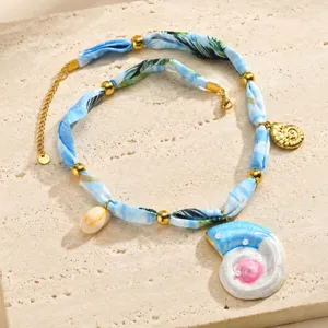 Collier ruban coquillage bohème en tissu imprimé bleu et perles dorées pour les vacances.