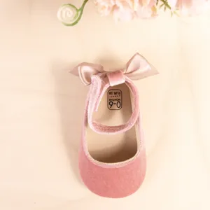 Pink velvet baby princess shoes detail shot, soft sole infant prewalker with bow.