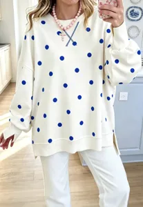 Detailed shot of women's loose polka dot sweatshirt with side slits and crew neck design.