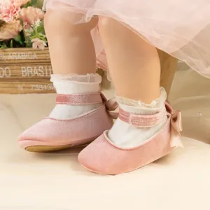 Close-up of cute baby pink velvet princess shoes with soft soles and sweet bow details.