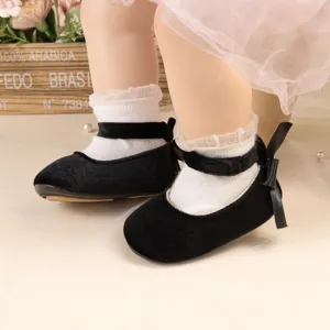 Cute infant velvet princess shoes with elegant bows and white socks for baby girl walking.