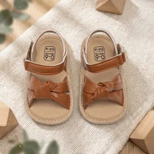 Brown baby sandals with cute knotted bow design, comfortable hook-and-loop closure for infants.