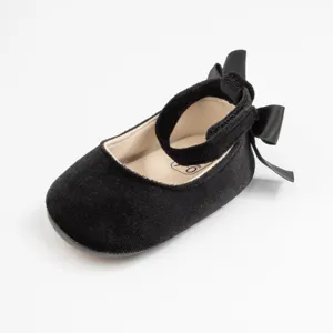 Detailed view of black velvet baby walking shoe featuring an elegant ankle strap and back bow.