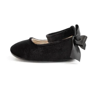 Detail close-up of black velvet baby shoe featuring a large satin bow at the heel strap.