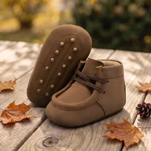 Braune Babylaufschuhe mit weichen Antirutschsohlen und Schnürung, gemütliche Herbstdetailansicht.