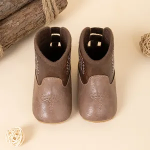 Détails en gros plan de bottes de cowboy pour bébé marron avec broderie et cuir PU.