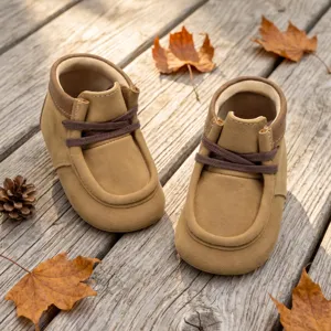 Nahaufnahme von weichen braunen Baby-Lauflernschuhen mit herbstlicher Blätter-Deko.