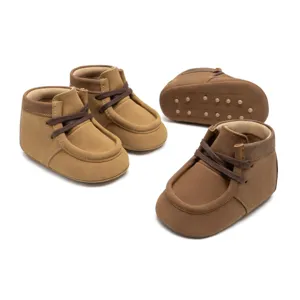 Nahaufnahme von braunen Babyschuhen aus Wildleder mit weicher Sohle und Schnürung.