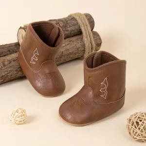 Bottes western en cuir PU marron pour bébé en gros plan, avec coutures blanches délicates.