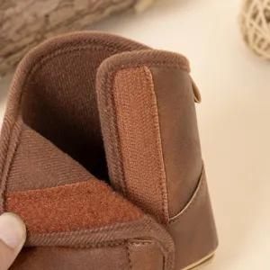 Détail de bottes d'hiver bébé en cuir PU marron, doublure polaire douce et fermeture velcro pratique.