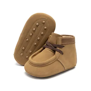 Braune Babyschuhe aus Wildleder mit weicher Sohle und Schnürung für Kleinkinder im Herbst.