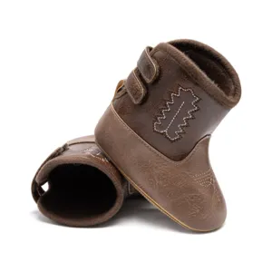 Gros plan sur des bottes de cowboy pour bébés marron, doublure peluche et broderie blanche.