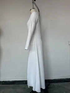 Side view detail of a elegant long sleeve white knit maxi dress showing texture and cut.