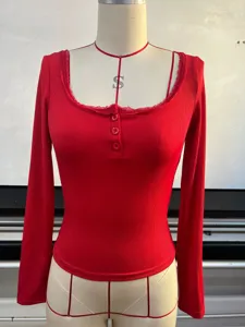 Détail de haut côtelé rouge à manches longues avec bordure en dentelle et boutons.