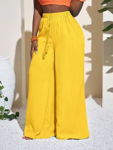 Close-up details of the yellow textured wide-leg pants showing the high waist and drawstring.