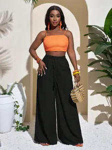 Outdoor scene detail showcasing textured black wide-leg trousers paired with an orange top.