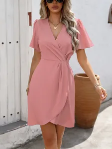 Vista dettagliata dell'elegante abito a portafoglio rosa con scollo a V, maniche corte e cintura.