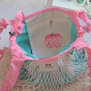 Detailed view of dopamine aesthetic nylon mesh bucket bag with pink ruffled straps and apple pocket.