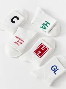 Men's white cotton mid-tube socks with stylish letter embroidery and streetwear design details.