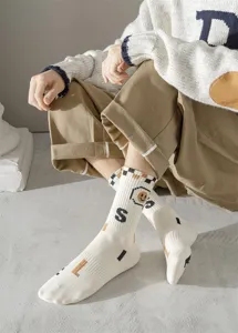 Vue détaillée des chaussettes montantes pour hommes avec smiley pixel et lettres.