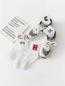 Detail view of men's cotton mid-tube white socks featuring stylish letter prints and embroidery.