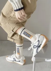 Vue détail des chaussettes mi-hautes en coton pour hommes associées à des baskets.