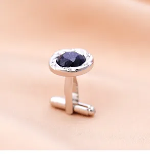 Gros plan de boutons de manchette homme en metal avec pierre bleue scintillante.