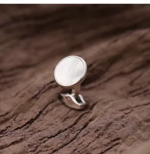 Détail de boutons de manchette ronds élégants en métal argenté avec nacre pour chemise.