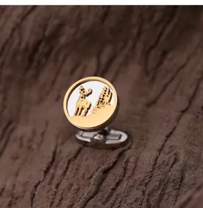 Gros plan de boutons de manchette dorés et argentés avec un design raffiné de cerf et d'arbres.