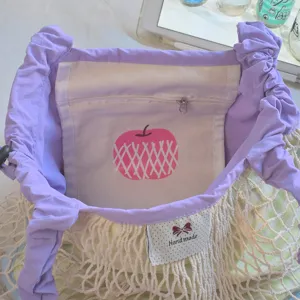 Purple drawstring net bag interior detail showing inner pocket with pink apple print.