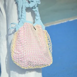 Detail shot of the cute dopamine style pink gingham net bag with blue ruffled straps.