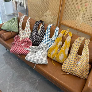 Detailed view showcasing multi-style printed canvas shoulder bags arranged nicely on leather sofa.
