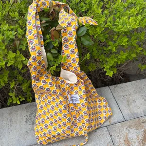 Detail shot of yellow floral cloth tote bag featuring knotted shoulder strap design.