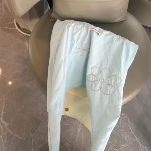 Gedetailleerde close-up van lichtblauwe nylon schoudertas met fijn bloemenborduurwerk.