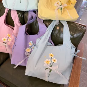 Leuke nylon schoudertas met schattig bloemborduursel en elegante witte kanten strikken.