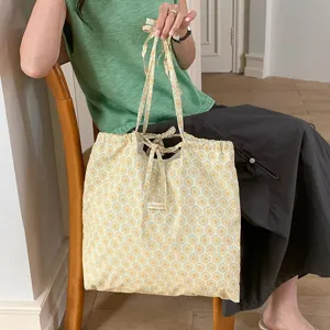 Dettaglio borsa a tracolla in tessuto floreale, chiusura con coulisse a nastro, borsa casual.