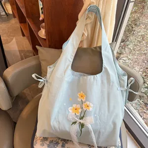Mooie leuke nylon schoudertas voor vrouwen met geborduurde bloemen en strik detail.