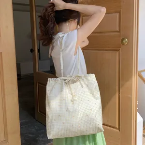 Borsa shopper in tela a quadri vichy giallo e bianco con stampa fiocco e chiusura a coulisse.