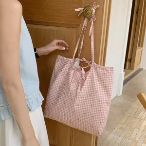 Vista dettagliata della borsa tote in tela a quadri rosa con graziosi fiocchi e spallacci.