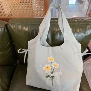 Gedetailleerd overzicht van de zoete stijl nylon bloem geborduurde schoudervesttas met kanten strik.